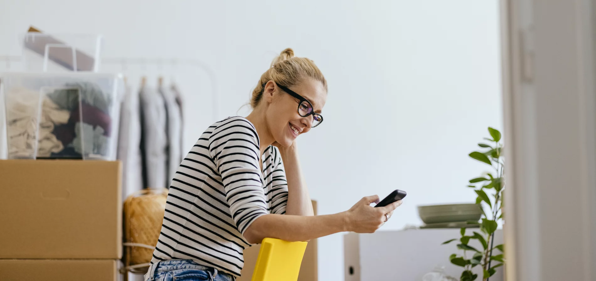 femme souriante avec son cellulaire dans un appartement